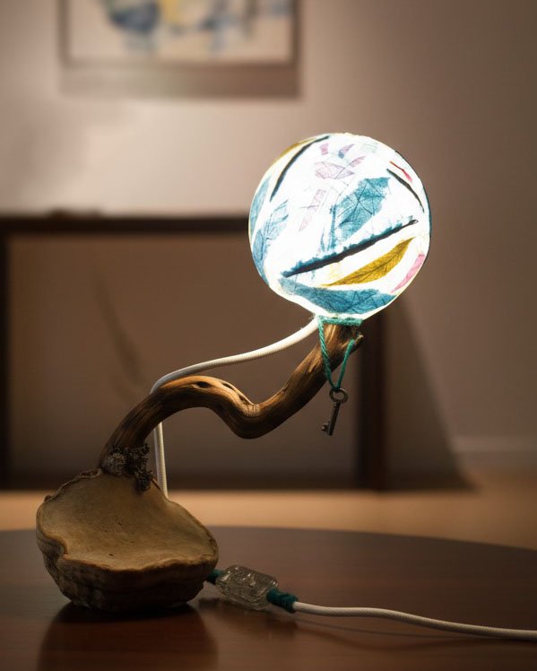 Lámpara de escritorio de diseño con brazo de madera curvado y pantalla redonda.